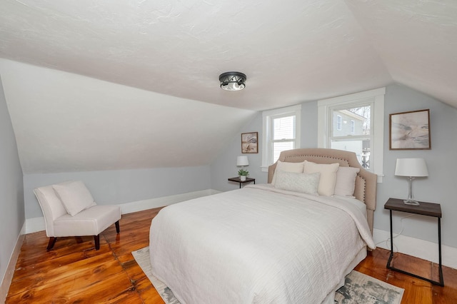 bedroom featuring baseboards, lofted ceiling, and wood finished floors