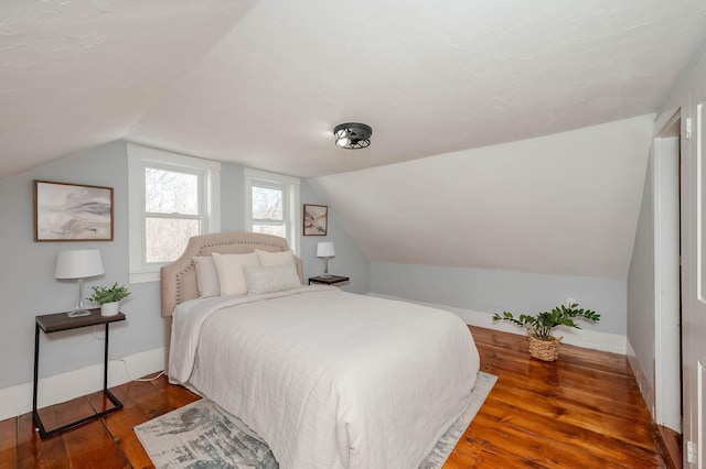 bedroom with baseboards, lofted ceiling, and wood finished floors