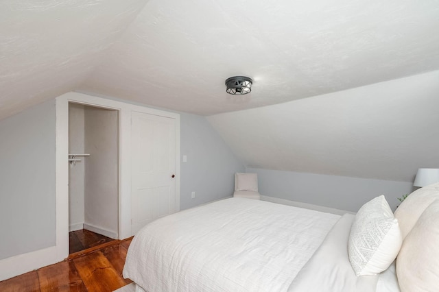 bedroom featuring a closet, lofted ceiling, and wood finished floors