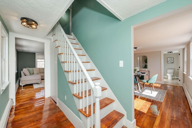 stairway with a textured ceiling, baseboards, and hardwood / wood-style flooring