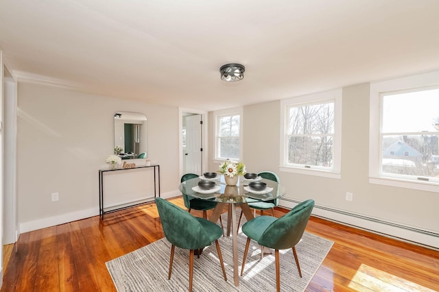 dining room featuring a baseboard heating unit, baseboards, and wood finished floors