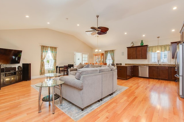 living area featuring a wealth of natural light, light wood-style flooring, and vaulted ceiling