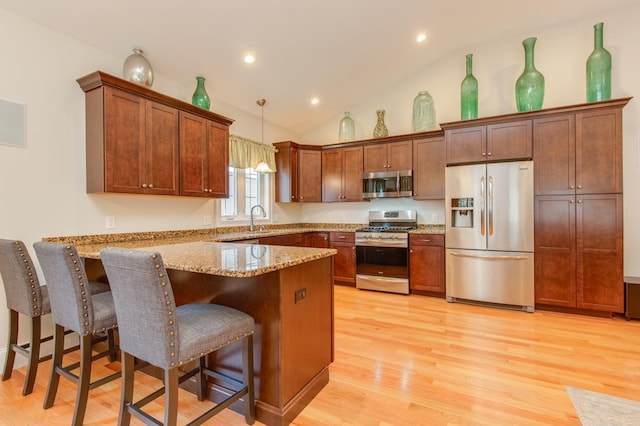 kitchen with light wood-style flooring, a sink, stainless steel appliances, a peninsula, and light stone countertops