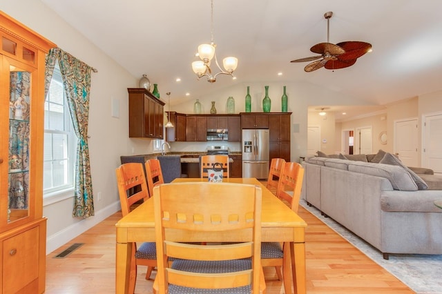 dining room featuring baseboards, visible vents, light wood-style flooring, vaulted ceiling, and ceiling fan with notable chandelier