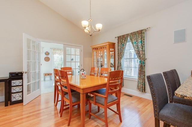 dining room with visible vents, light wood-style flooring, french doors, and lofted ceiling