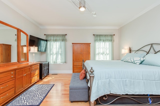 bedroom with multiple windows, crown molding, and light wood finished floors