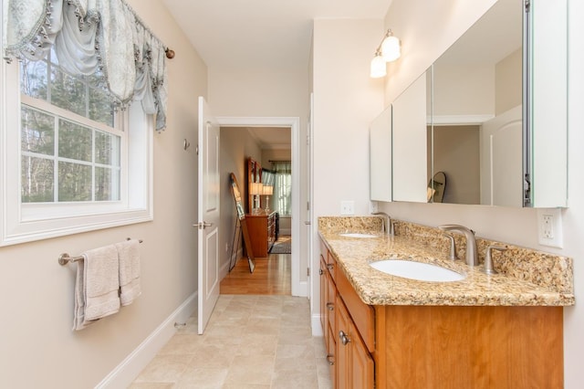 bathroom featuring double vanity, baseboards, and a sink