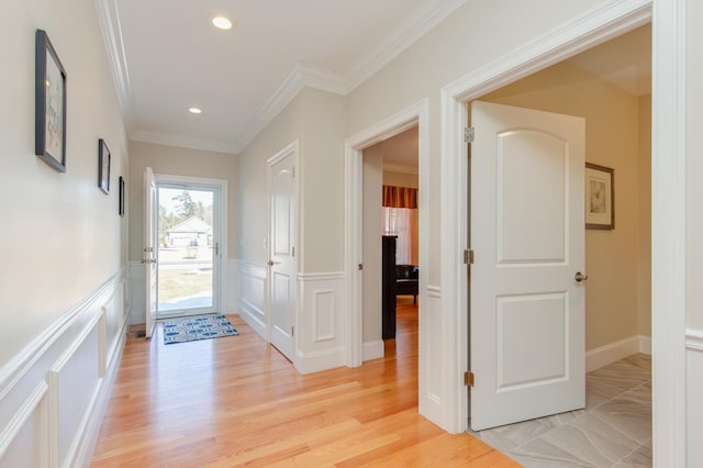 foyer entrance with light wood-type flooring, ornamental molding, recessed lighting, wainscoting, and a decorative wall