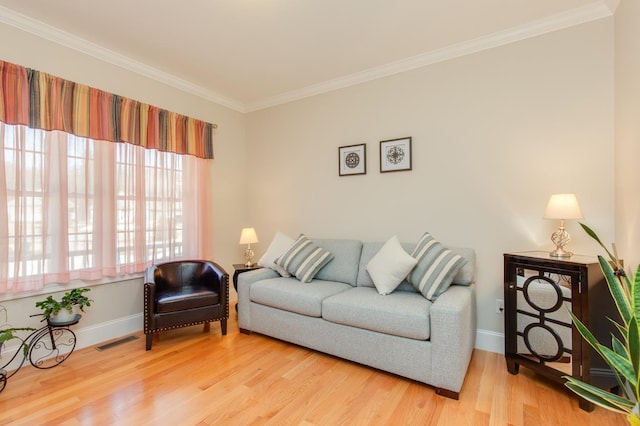 living area featuring visible vents, baseboards, crown molding, and light wood finished floors