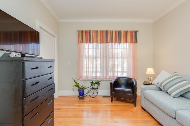 living area with crown molding, light wood-style floors, and baseboards