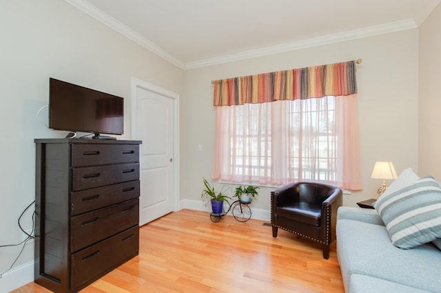 living area with crown molding, light wood-style flooring, and baseboards