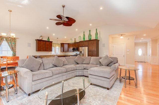 living room featuring recessed lighting, ceiling fan with notable chandelier, light wood-style flooring, and vaulted ceiling