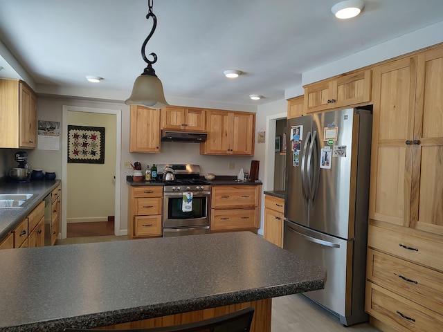 kitchen featuring a sink, stainless steel appliances, under cabinet range hood, pendant lighting, and dark countertops