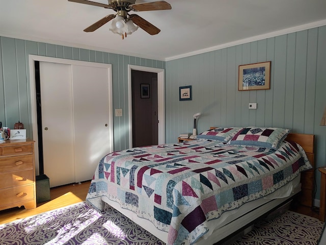 bedroom featuring a closet, ornamental molding, ceiling fan, and wood finished floors