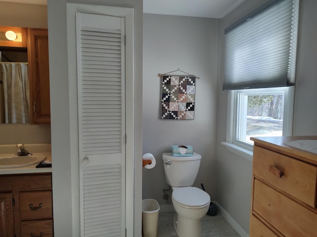 bathroom with vanity, toilet, baseboards, and a closet