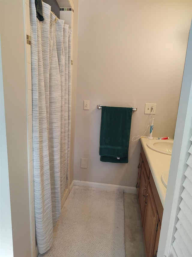 full bathroom with a shower with curtain, double vanity, baseboards, and a sink