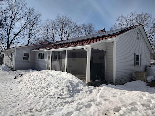 snow covered property featuring an attached carport and a sunroom