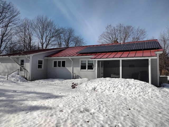 exterior space featuring metal roof, roof mounted solar panels, a chimney, and a standing seam roof