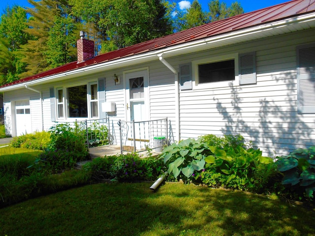 view of front of house with a front lawn, a standing seam roof, covered porch, metal roof, and a chimney