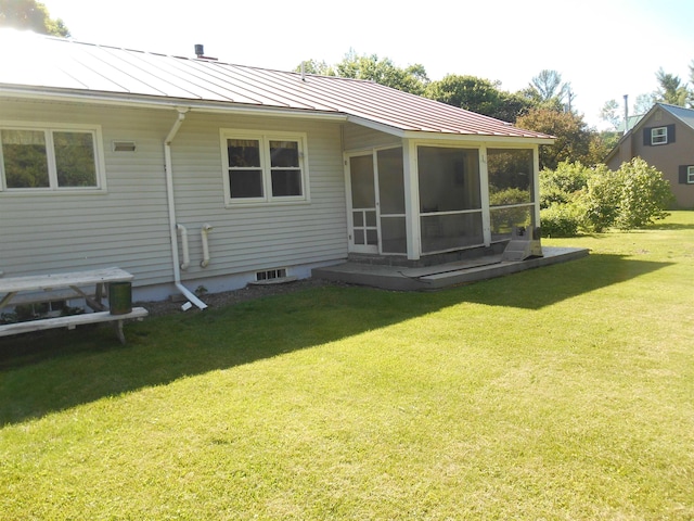 back of property with a yard, metal roof, a standing seam roof, and a sunroom