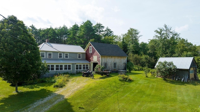 exterior space featuring metal roof, an outbuilding, a lawn, and driveway