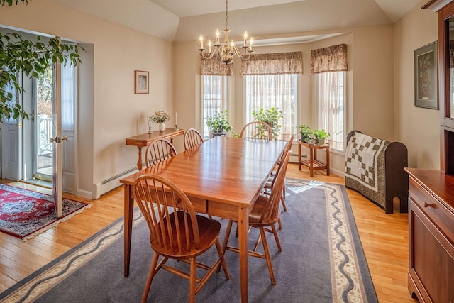 dining area featuring vaulted ceiling, light wood-style flooring, baseboards, and a chandelier