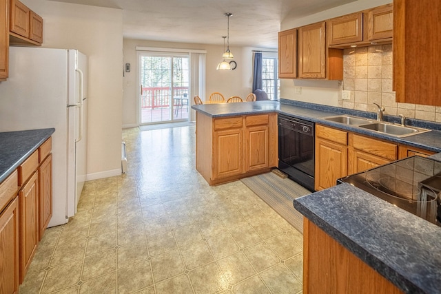 kitchen featuring dark countertops, dishwasher, a peninsula, freestanding refrigerator, and a sink