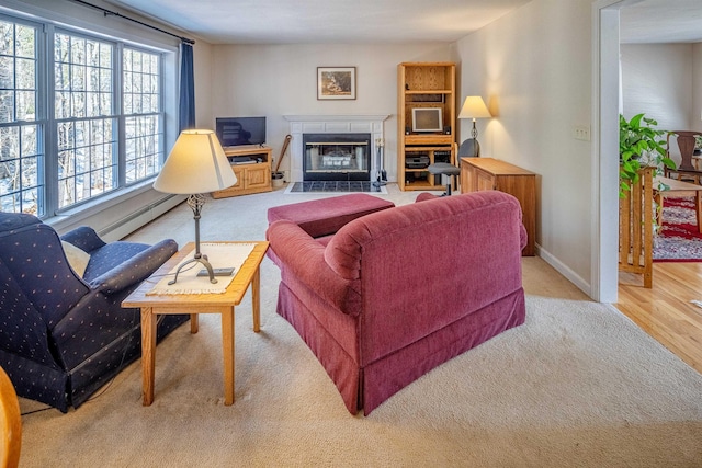 living room featuring a baseboard heating unit, a fireplace with flush hearth, wood finished floors, and baseboards