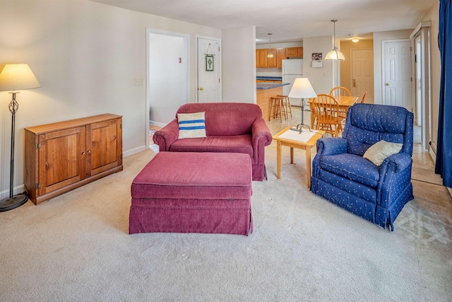 living area featuring light carpet and baseboards