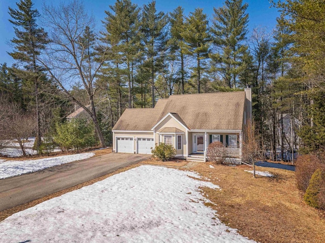 view of front of property featuring aphalt driveway, an attached garage, a porch, and a chimney