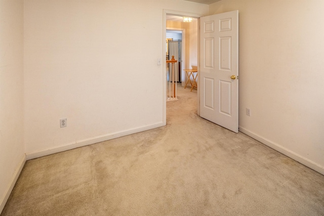 unfurnished room featuring baseboards and light carpet