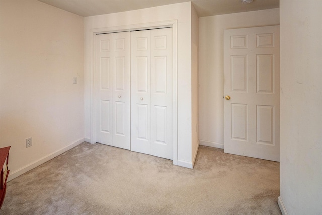 unfurnished bedroom with carpet flooring, baseboards, and a closet