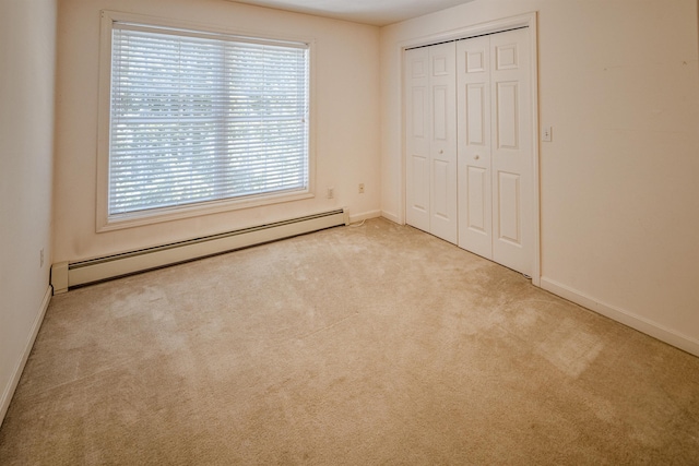 unfurnished bedroom with a closet, baseboard heating, carpet flooring, and baseboards