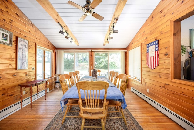 dining room with a baseboard heating unit, lofted ceiling with beams, wooden walls, and a baseboard radiator