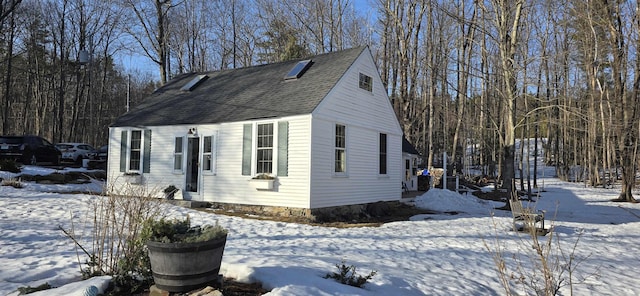 snow covered property with roof with shingles