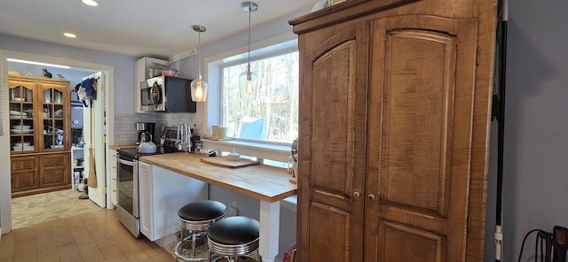 kitchen with stainless steel appliances, decorative backsplash, hanging light fixtures, wood counters, and brown cabinets