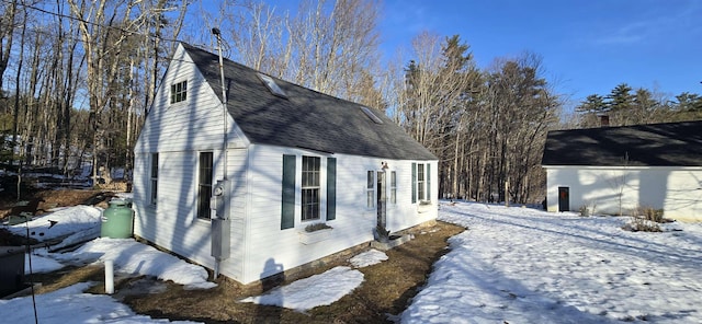 view of snowy exterior with roof with shingles