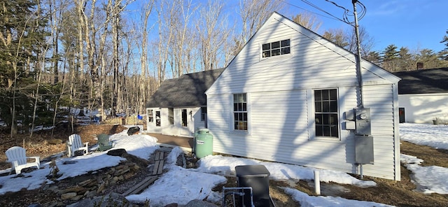 snow covered property with a shingled roof