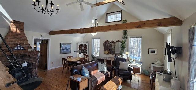 living room featuring beam ceiling, ceiling fan with notable chandelier, wood-type flooring, baseboards, and a wood stove