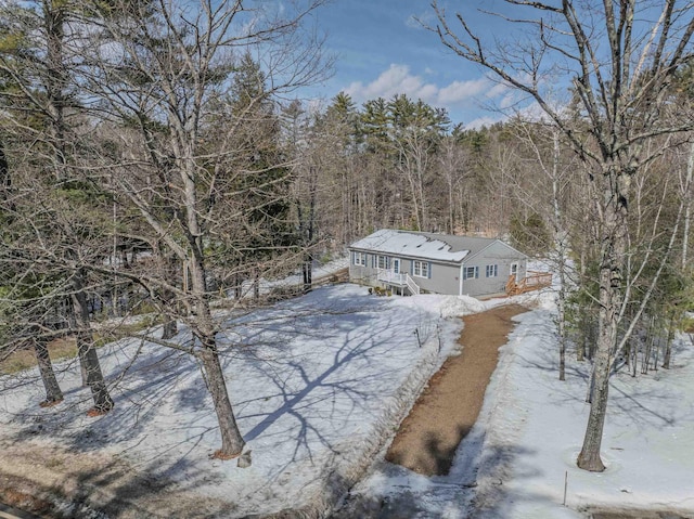 snowy aerial view featuring a wooded view