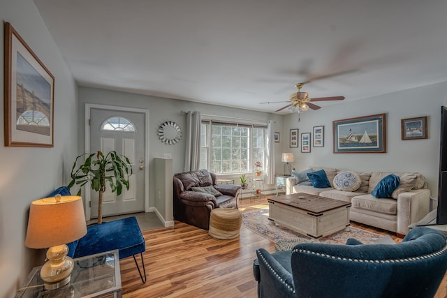 living area with light wood-type flooring, baseboards, and a ceiling fan