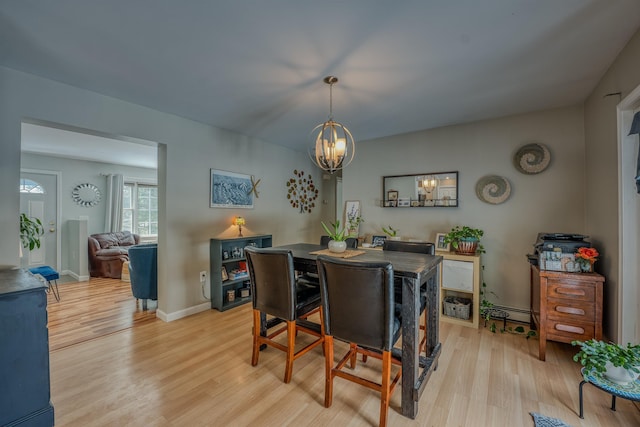 dining room with an inviting chandelier, baseboards, and light wood-type flooring