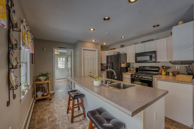 kitchen featuring a baseboard radiator, recessed lighting, a sink, black appliances, and white cabinetry