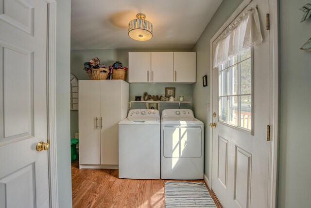 clothes washing area featuring cabinet space, separate washer and dryer, and light wood finished floors