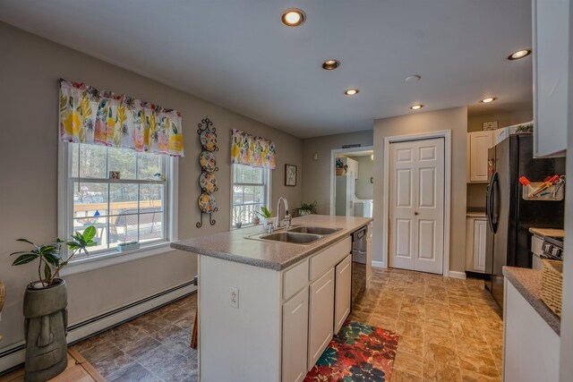 kitchen with a sink, a baseboard heating unit, black appliances, and a center island with sink