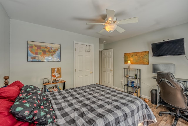 bedroom with a ceiling fan, wood finished floors, and baseboards