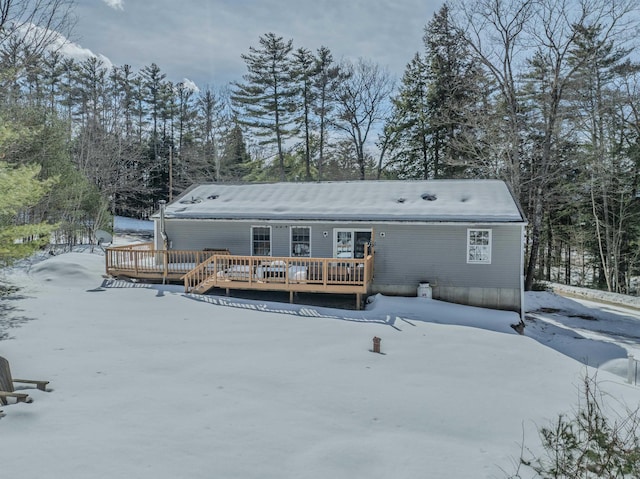 snow covered back of property featuring a wooden deck