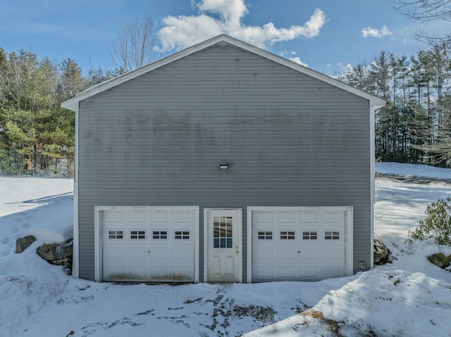 snow covered property with a detached garage