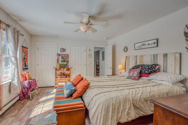 bedroom featuring a baseboard heating unit, wood finished floors, and a ceiling fan