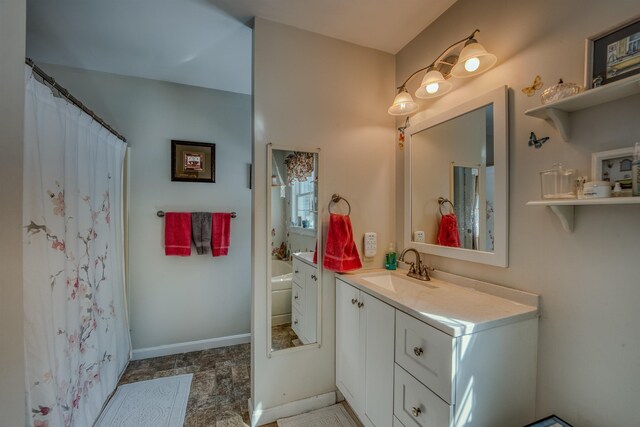 full bath with vanity, a bathing tub, and baseboards